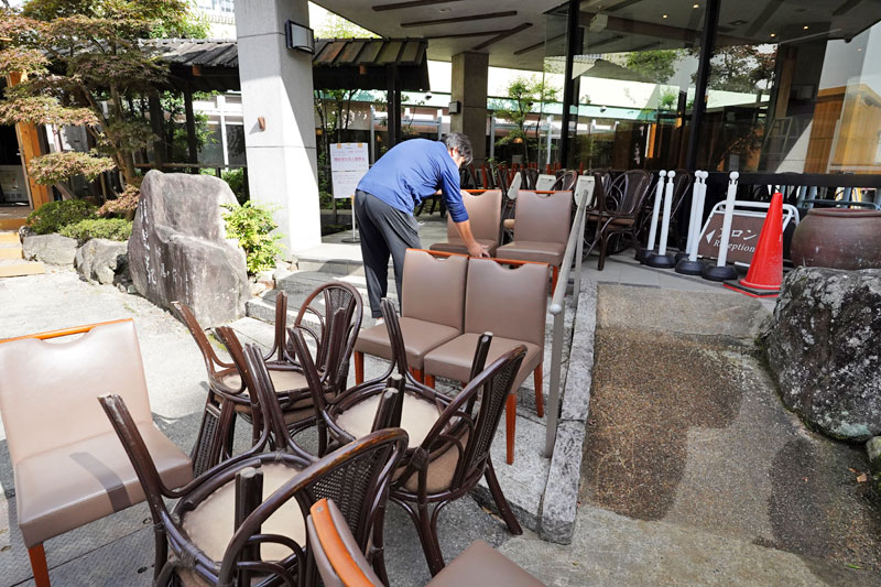 【復旧】営業再開に向けた掃除のため椅子を外に出す従業員
