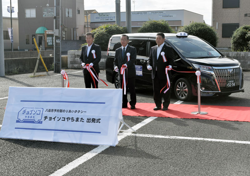 八街市予約型乗り合いタクシーの出発式でテープカットする北村市長(中央)ら=2日、市役所駐車場