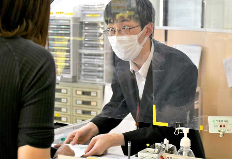 ネクタイをしないジャケット姿で市民に対応する富里市役所の職員