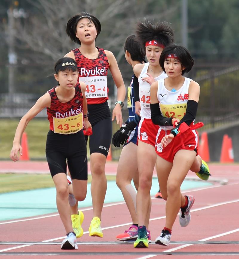 女子　４区から５区へたすきをつなぐ流通経大柏（左）と成田の選手ら＝東総運動場