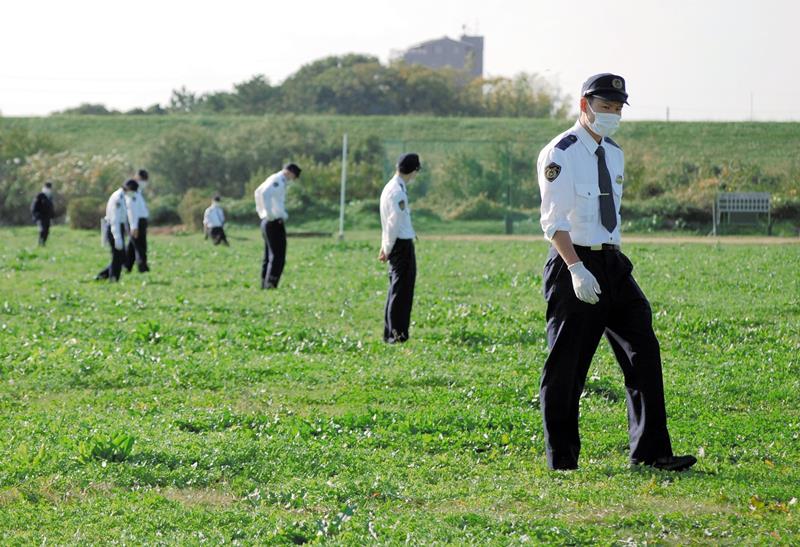 現場近くの江戸川河川敷を捜索する警察官＝９日午後１時５０分ごろ、松戸市古ケ崎