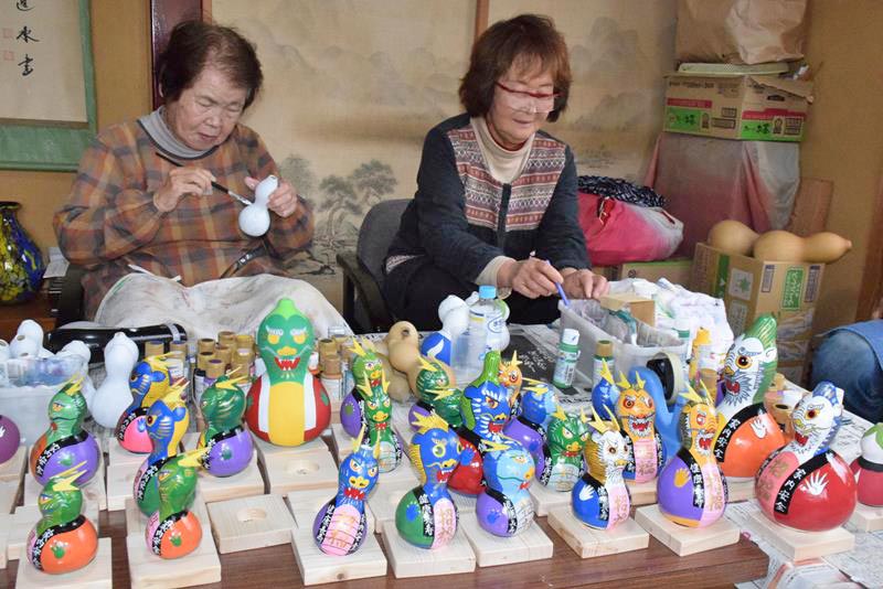 ヒョウタンへの絵付け作業を進める住民たち。来年の主役「辰」の置物が次々に仕上がった=匝瑳市