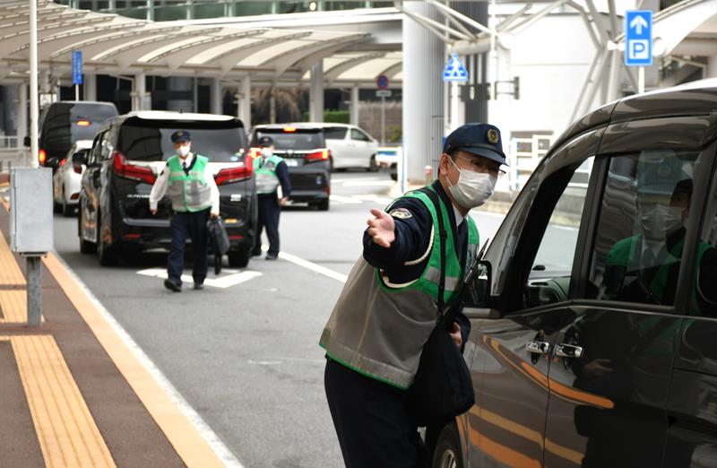 成田空港第1ターミナルの乗降場に駐車する車の運転手に移動を促す警察官=11日、成田市