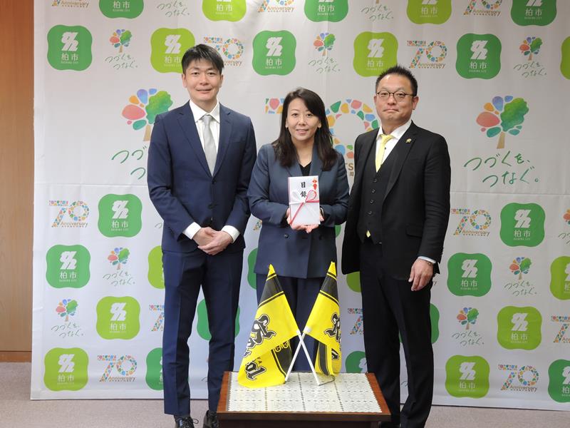 集まった寄付金の目録を太田市長(中央)に渡したレイソル後援会の鴇田実行委員長(右)と近藤さん=柏市役所