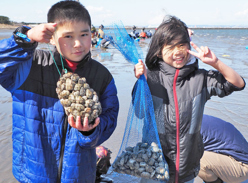 網袋いっぱいになったアサリやハマグリを手に喜ぶ子どもたち＝９日、富津市