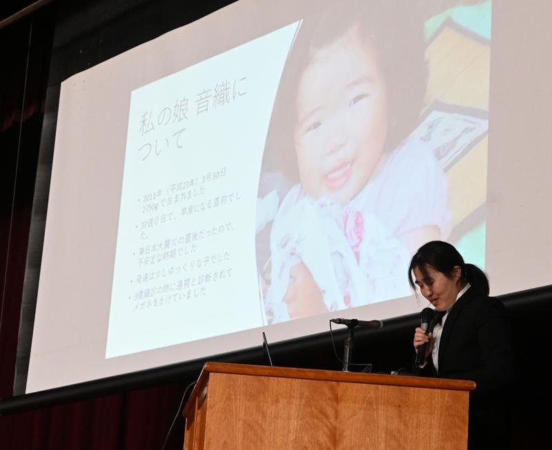 スクリーンに映し出された音織さんの写真の前で講演する安藤さん＝１８日、千葉市緑区の県立土気高校