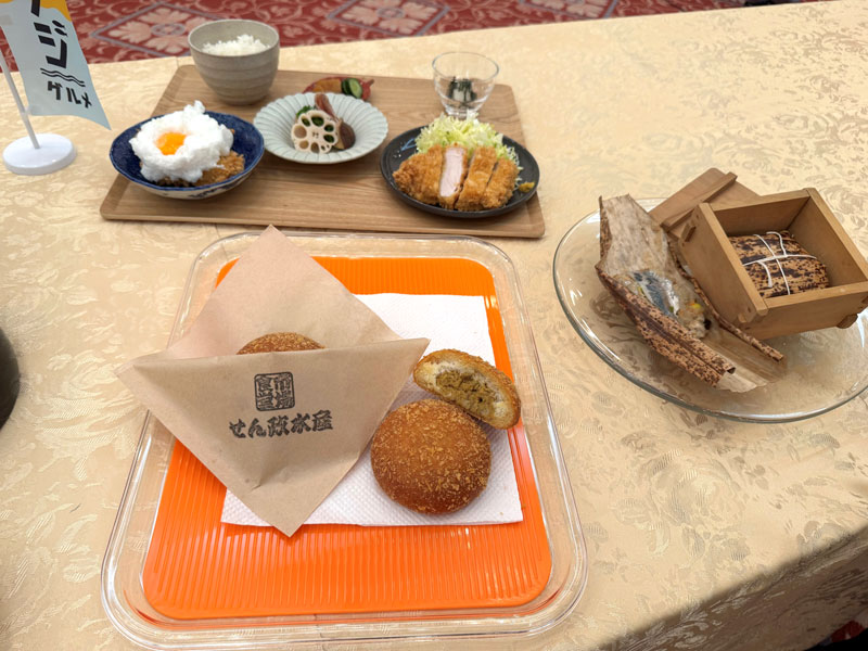 「市場食堂せん政水産」が開発した「あじカレーパン」（中央）。右は「とんかつ屋みやはん」が考案した「アジ飯のちまき」