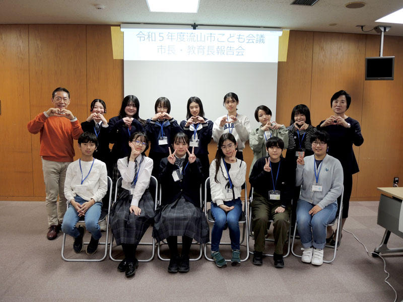 流山市こども会議の報告会終了後に、井崎市長(後列左端)や田中弘美教育長(同右端)と記念撮影する委員ら=3月16日、同市