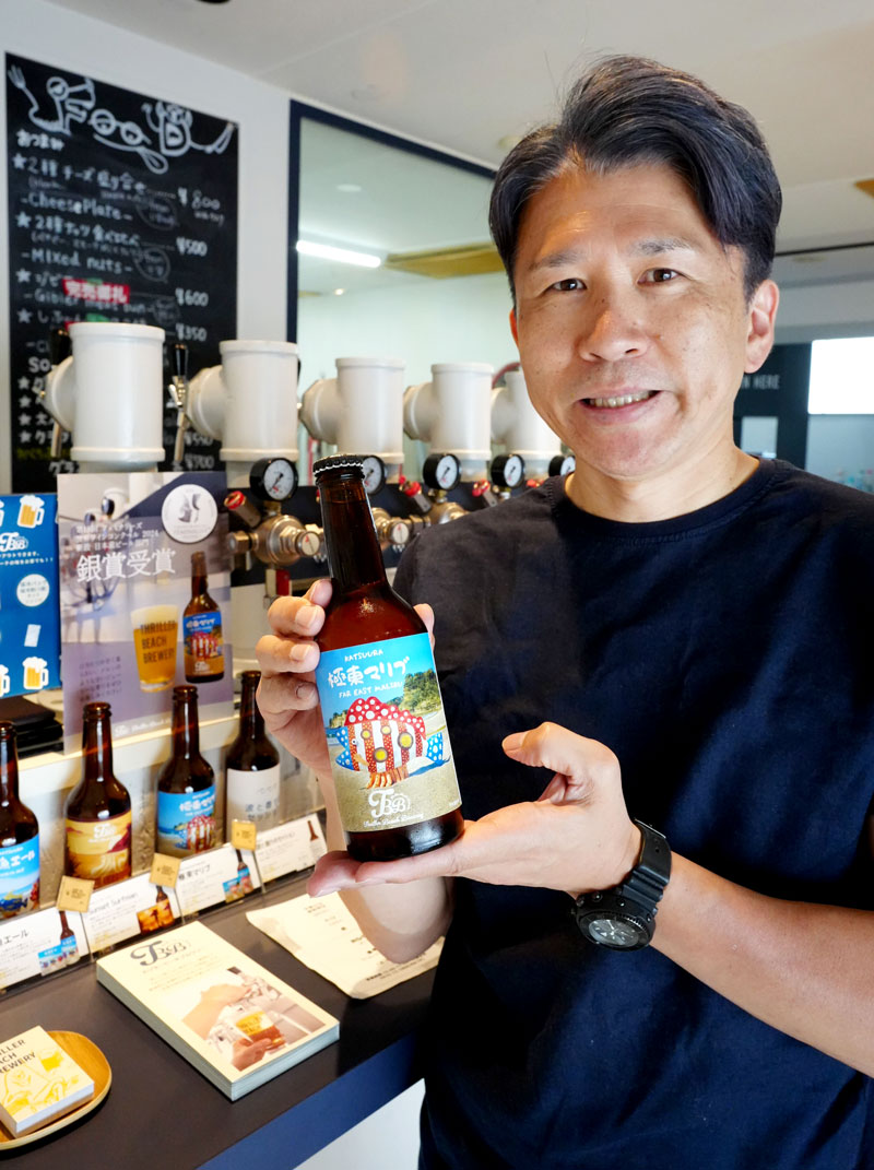 「極東マリブ」の瓶ビールを持つ笠倉代表=勝浦市