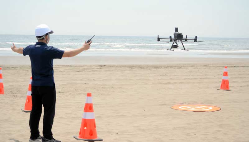 救助の実演で飛行する大型のドローン＝８日、山武市