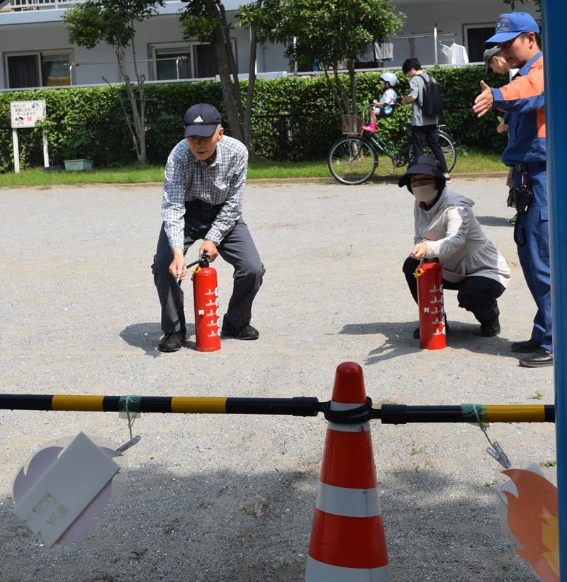 練習用の消火器で使い方を確認する来場者ら＝船橋市