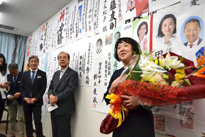花束を手に支持者へ感謝を述べる立憲民主党の野田氏の仁実夫人＝２７日、船橋市