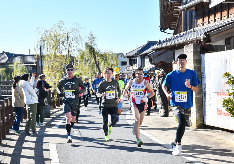 歴史的な建造物が立ち並ぶ佐原の町並みを駆け抜けるランナーら=15日、香取市