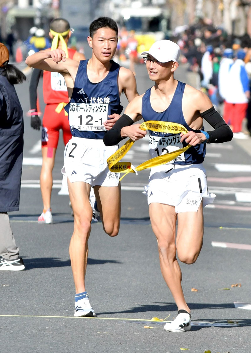 １区日本人最高記録を更新し、たすきをつなぐ八千代松陰の鈴木琉胤（左）。右は２区上杉敦史＝２２日、京都市