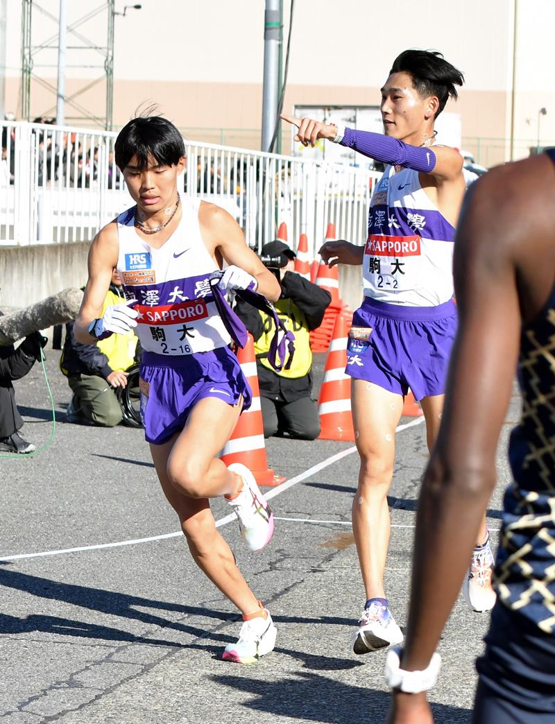 戸塚中継所でたすきをつなぐ駒大の篠原倖太朗(右)=横浜市戸塚区