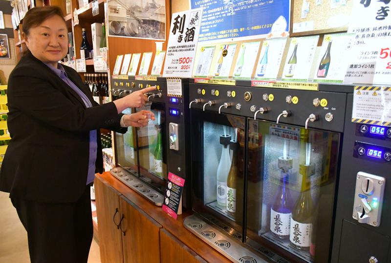 成田山参道に構える滝沢本店で日本酒の試飲サーバーを紹介する滝沢副社長。500円で最大3種類楽しめる気軽さが外国人観光客らに好評だという=成田市