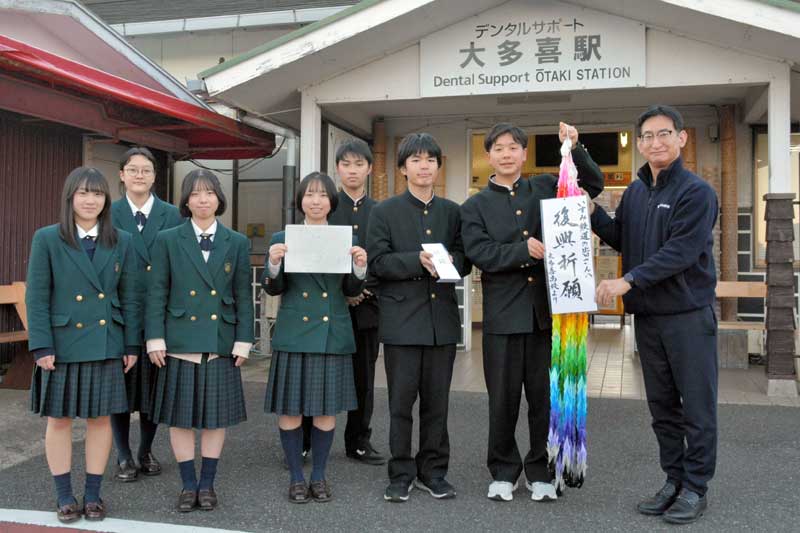 いすみ鉄道の早急運行再開を願い、大多喜高生から古竹社長(右)に手渡された千羽鶴と寄付金=10日、大多喜町