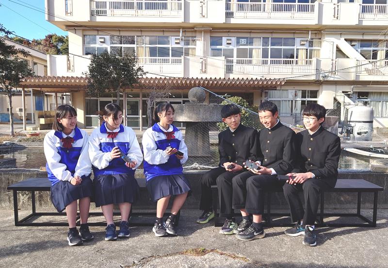 ペンケースを持ちアップサイクルされたベンチに座り談笑する南総中の生徒＝市原市