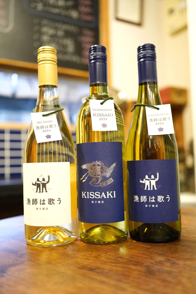 2024年度醸造の新酒の白ワイン。タグひもには漁網を使い、KISSAKI(中央)のラベルに描かれる鶴は漁師の伝統的祝い着「万祝」の絵柄からデザイン