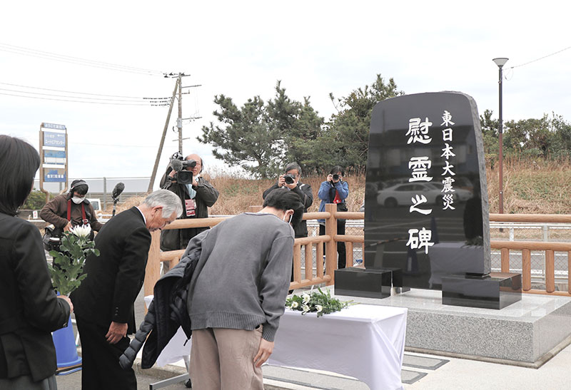 慰霊碑の前で犠牲者の冥福を祈る人たち＝１１日、旭市