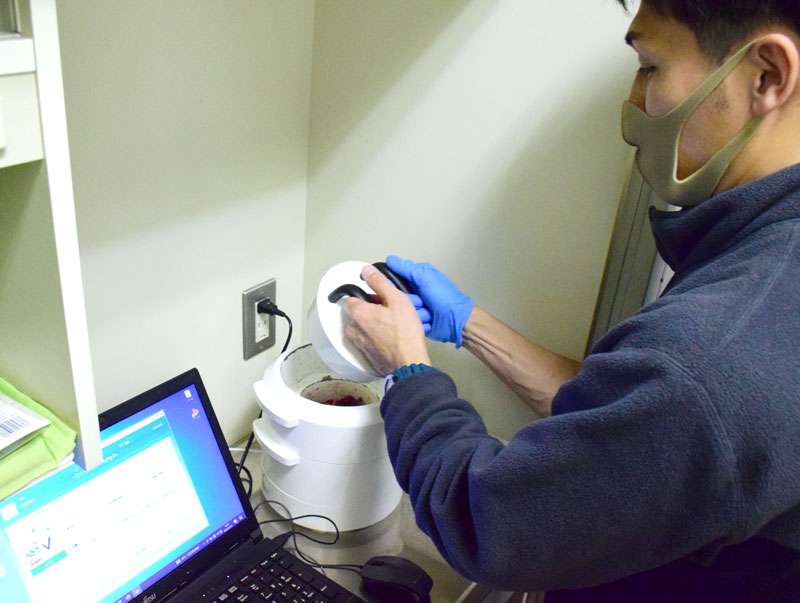 放射性物質の検査機器にイノシシの検体を入れる市職員＝茂原市役所