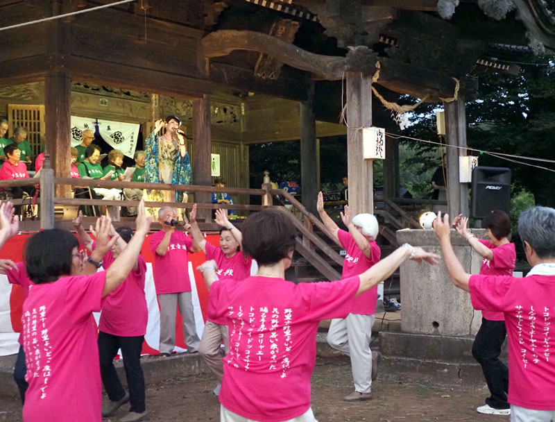 復活した「野里音頭」のお披露目。社殿上で峰丘奈知さんが歌い、住民の踊りの輪ができた＝袖ケ浦市