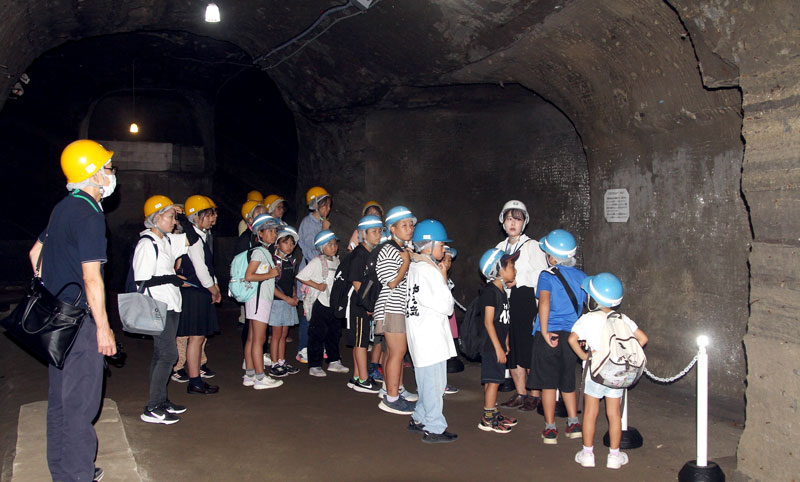 赤山地下壕跡を見学する神余小学校の児童や保護者、卒業生ら。水島学芸員の案内のもと、公開されている壕内の２５０メートルをくまなく見て回った