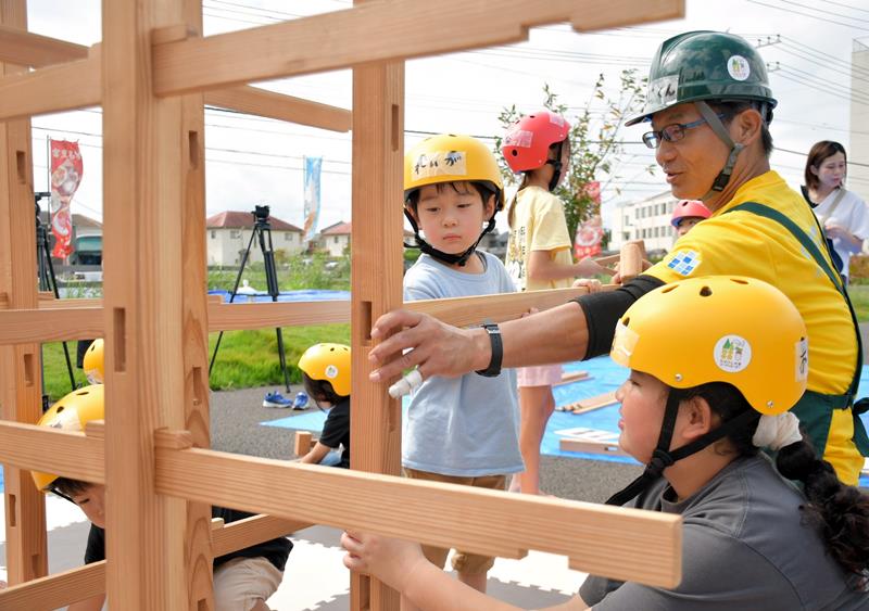 木育コーディネーターの竹内さんに習って木製のジャングルジムを組み立てる子どもたち=富里市