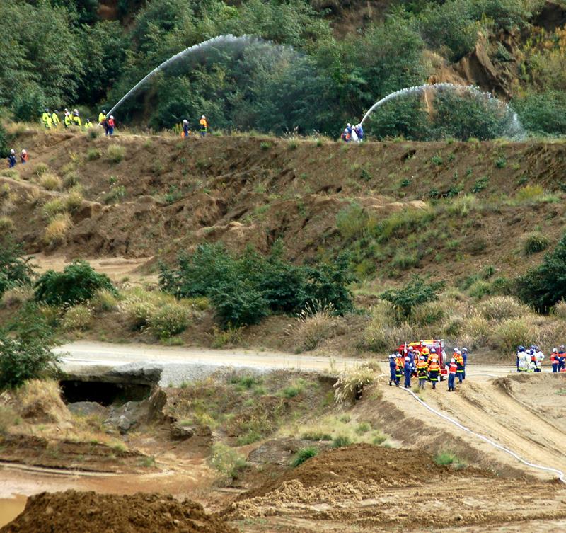ポンプで長い距離をつないだホースから放水する訓練を行う消防団員＝１６日、市原市万田野