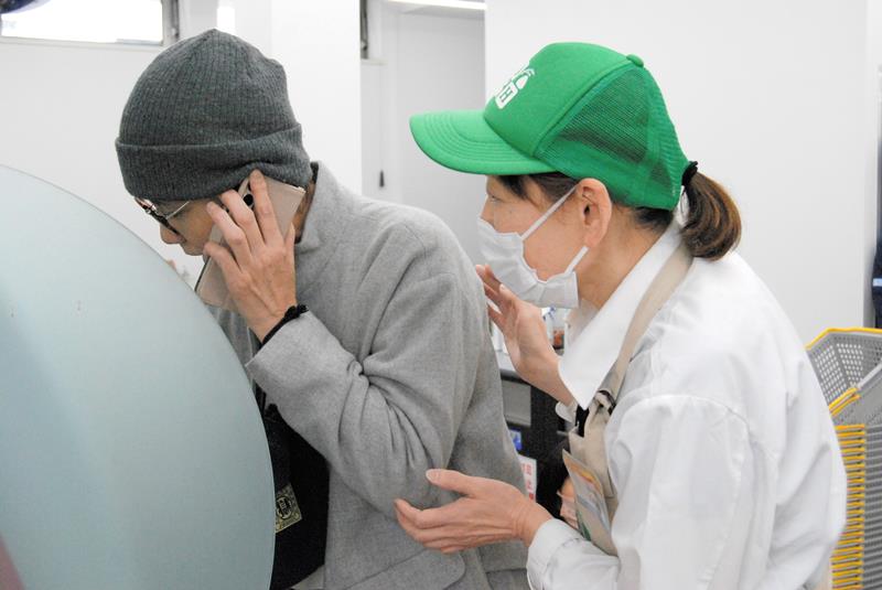 電話をしながらＡＴＭを操作する来店客への声かけ訓練に臨むコンビニ店員＝６日、柏市豊四季のデイリーヤマザキ豊四季駅北口店
