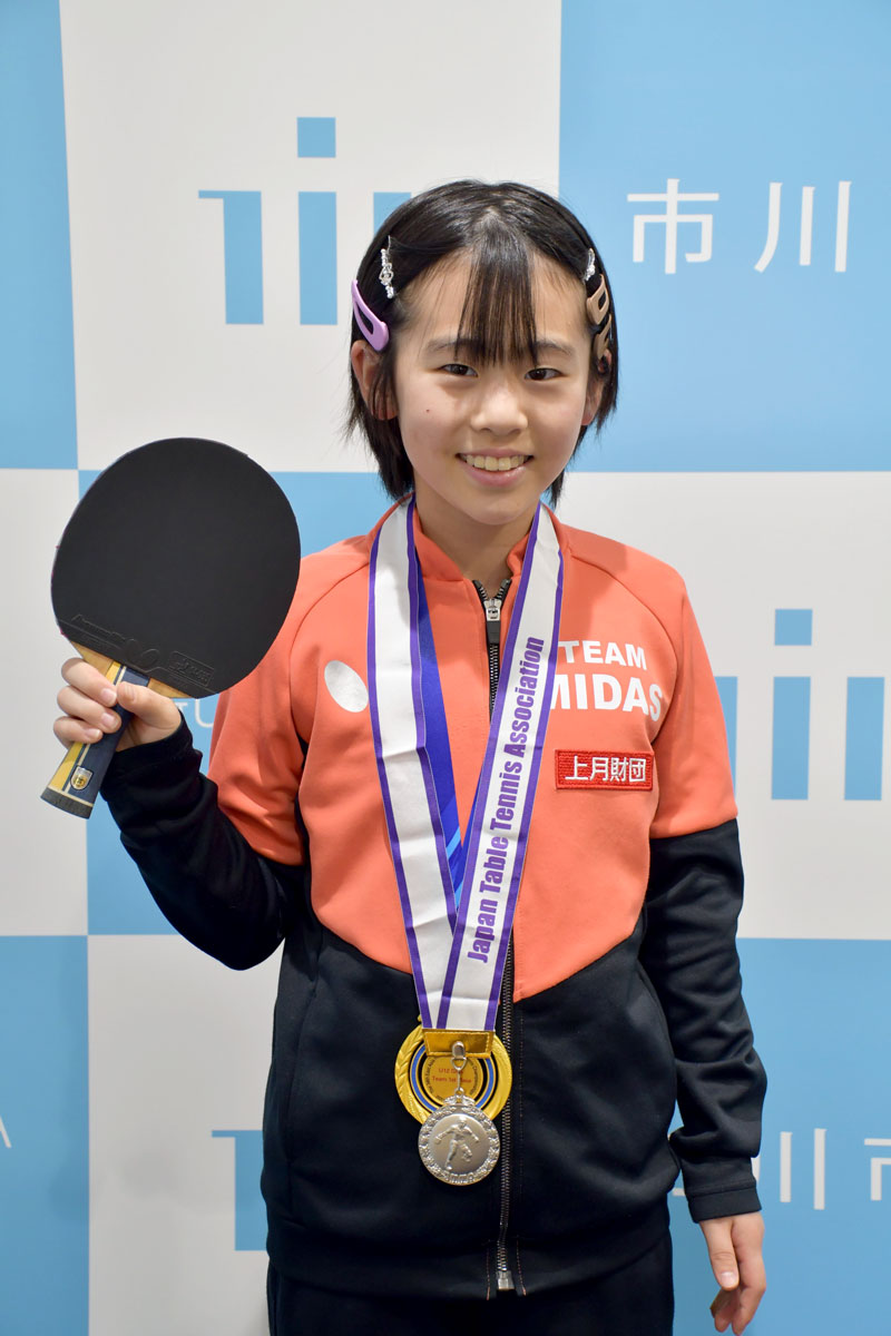 愛用のラケットを手に笑顔の鈴木さん＝市川市役所