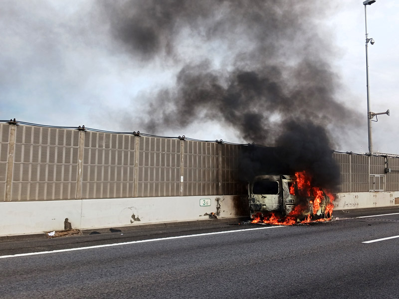 東関道下りの車線脇で炎上する車=15日午後1時55分ごろ、船橋市