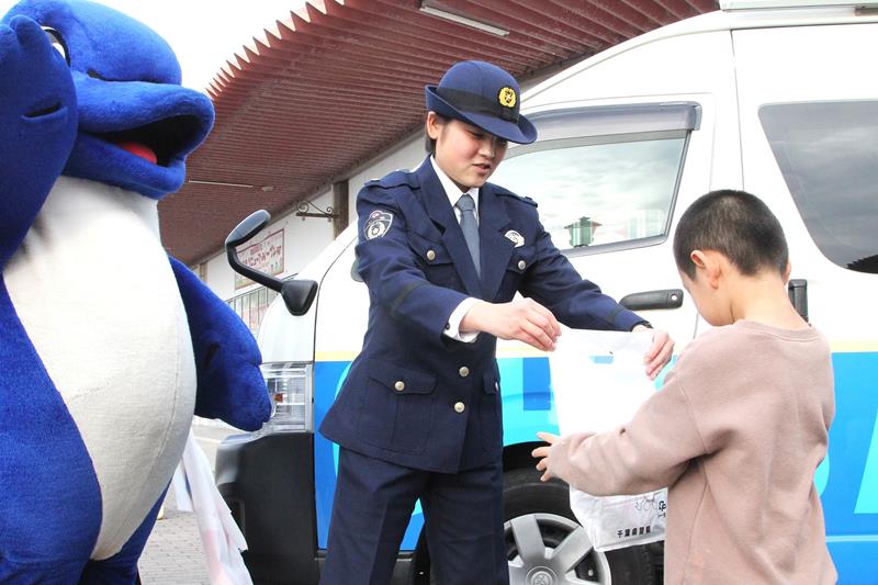啓発グッズを子どもに配る四本巡査＝館山市