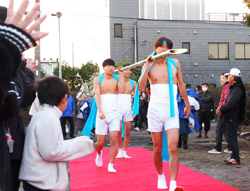下帯にたすき姿で現れ、御幣をつけた青竹を担いで海に向かう若者たち＝１０日、木更津市