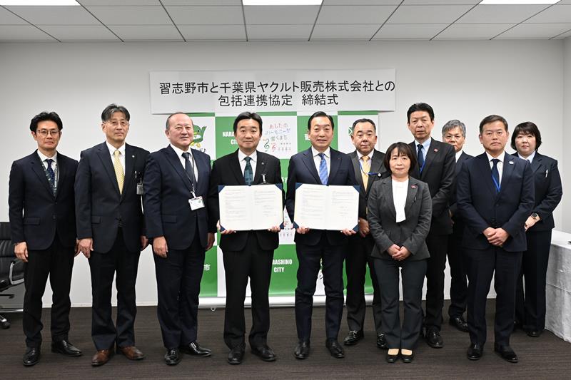 協定書を手にする宮本市長（左から４人目）と赤田社長（同５人目）＝習志野市役所