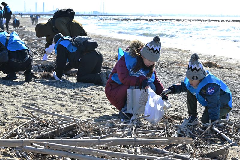 海岸のマイクロプラスチックを拾い集める参加者たち＝２４日、千葉市美浜区